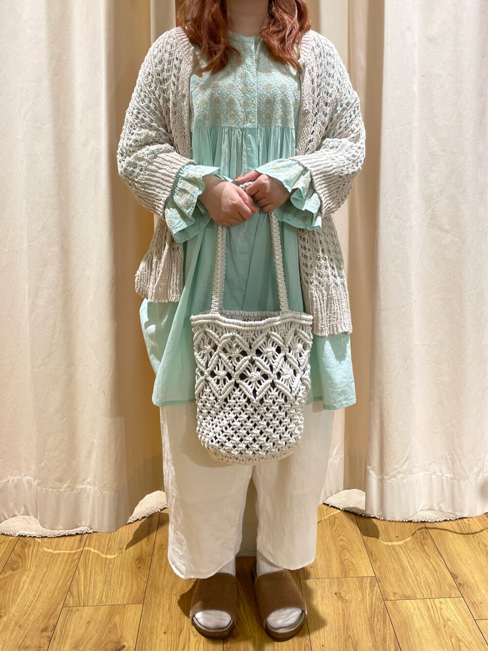 イエロー系のサンダル、ホワイト系のカーディガン/ボレロ、グリーン系のチュニックを着用したレディースの夏コーディネートの2枚目の写真