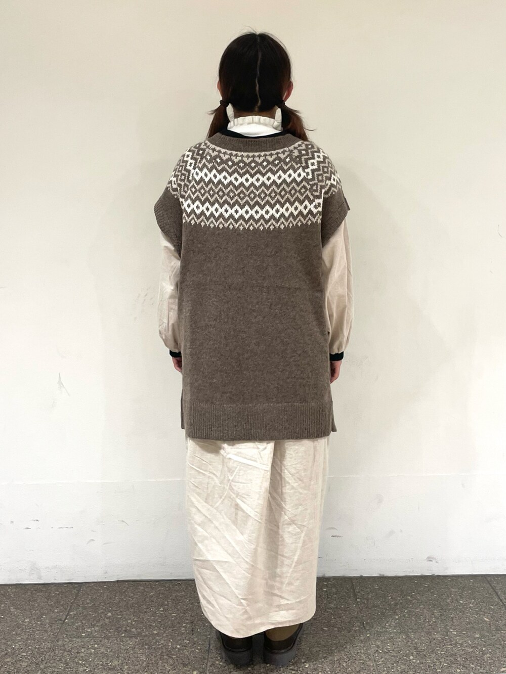 ベージュ系のワンピース、ブラウン系のベスト、ブラウン系のその他パンツを着用したレディースの冬コーディネートの3枚目の写真