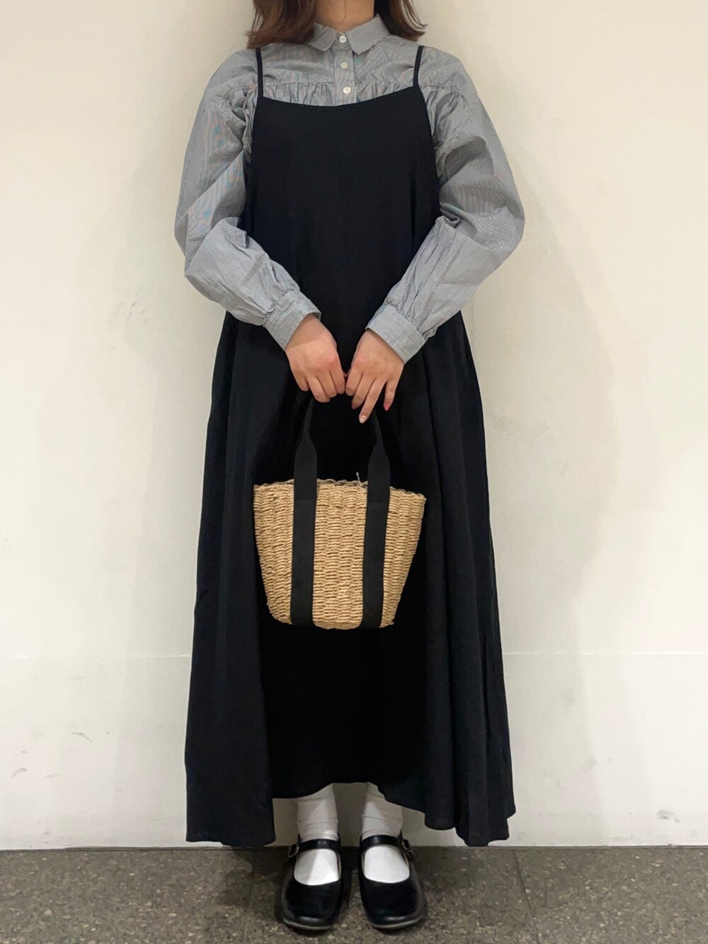 ブルー系のチュニック、ブラック系のワンピース、ブラック系のハンドバッグを着用したレディースの春コーディネートの2枚目の写真