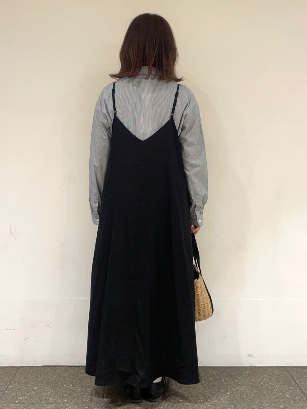 ブルー系のチュニック、ブラック系のワンピース、ブラック系のハンドバッグを着用したレディースの春コーディネートの4枚目の写真