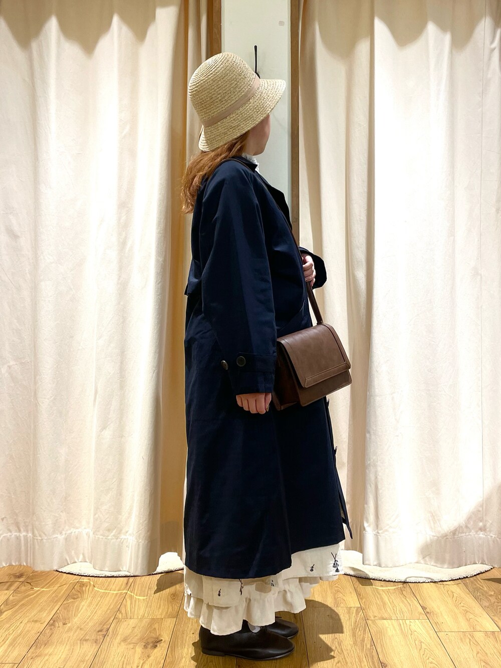 ブラウン系のその他シューズ、ホワイト系のワンピース、ブルー系のトレンチコートを着用したレディースの冬コーディネートの2枚目の写真