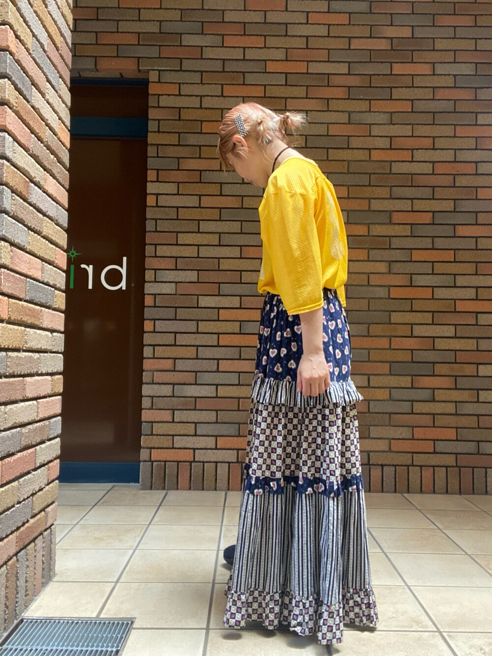 イエロー系のトップス、その他のスカート、ブラック系のスニーカーを着用したレディースの夏コーディネートの2枚目の写真