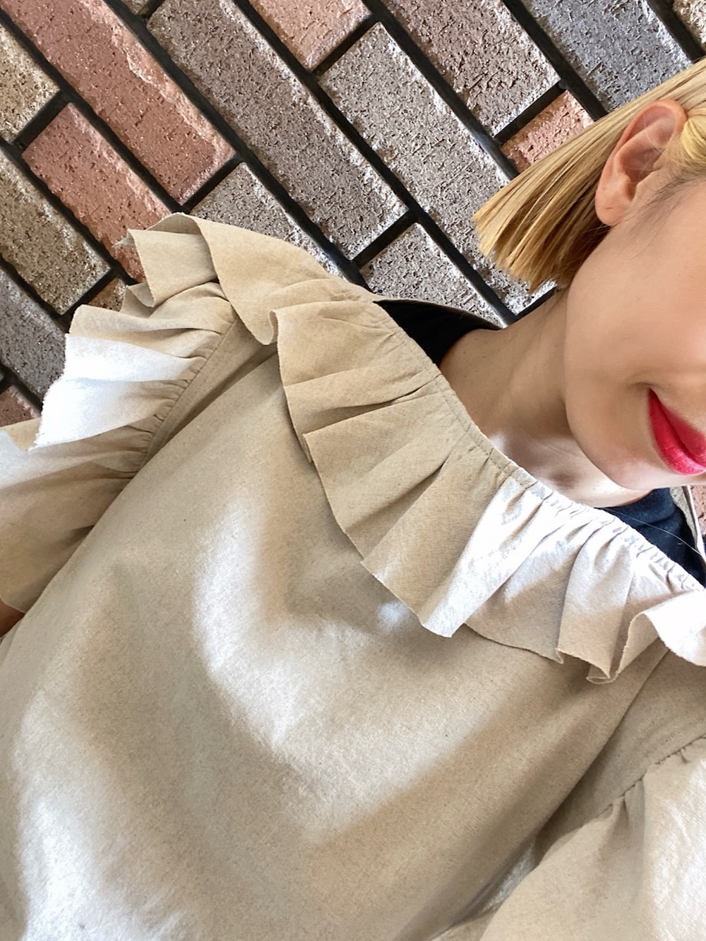 ベージュ系のトップス、ホワイト系のスカート、ブラック系のスニーカーを着用したレディースの夏コーディネートの2枚目の写真