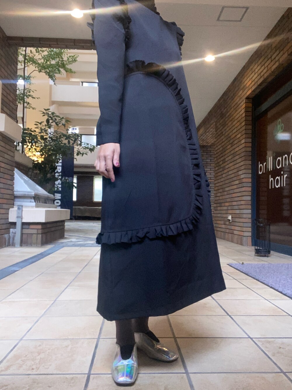 シルバー系のパンプス、ブラック系のワンピースを着用したレディースの秋コーディネートの2枚目の写真