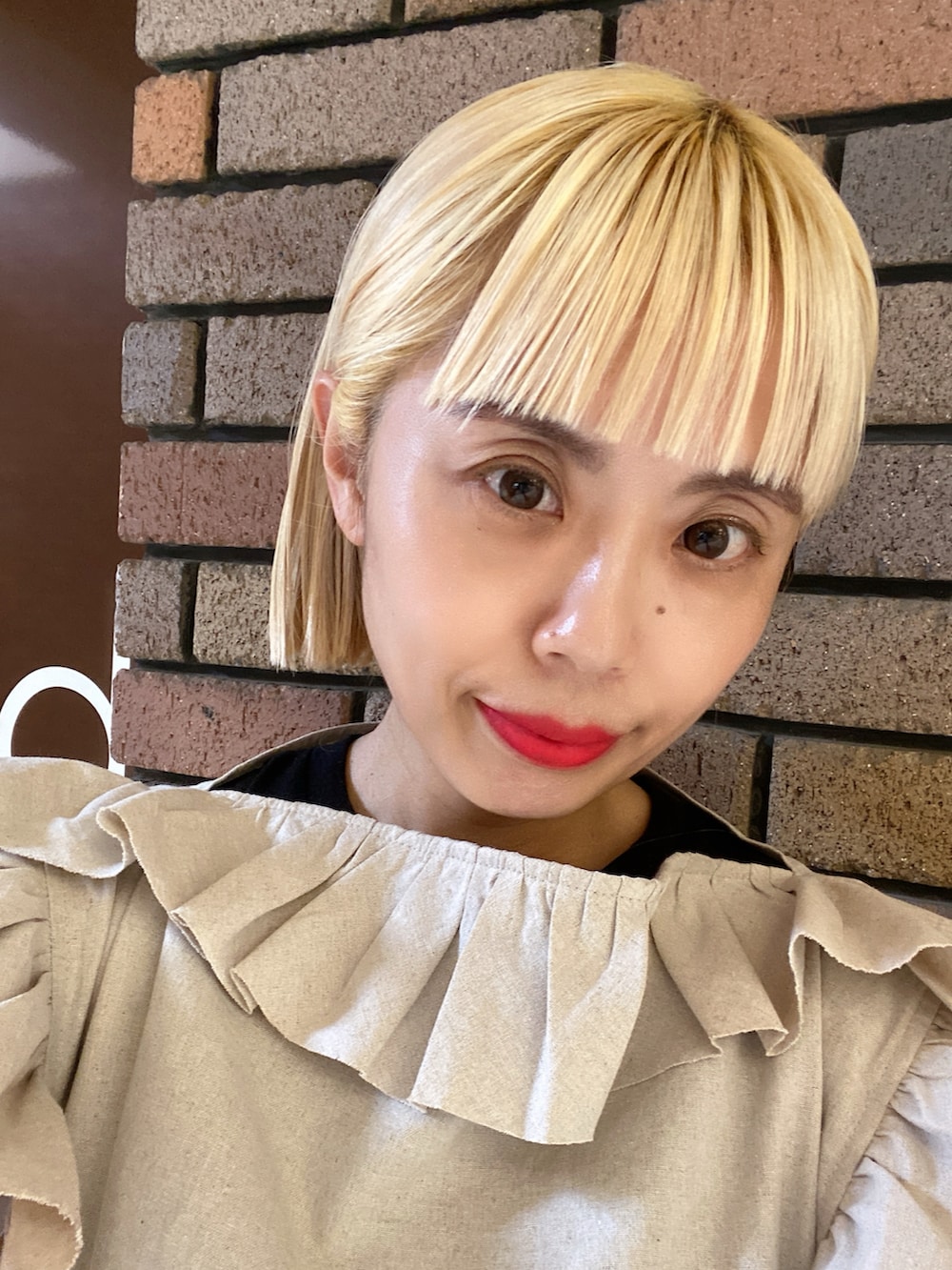 ベージュ系のトップス、ホワイト系のスカート、ブラック系のスニーカーを着用したレディースの夏コーディネートの3枚目の写真