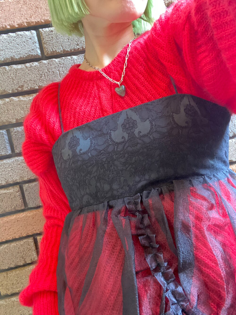 ブラック系のワンピース、レッド系のニット/セーター、ブラック系のスウェットパンツを着用したレディースの冬コーディネートの3枚目の写真