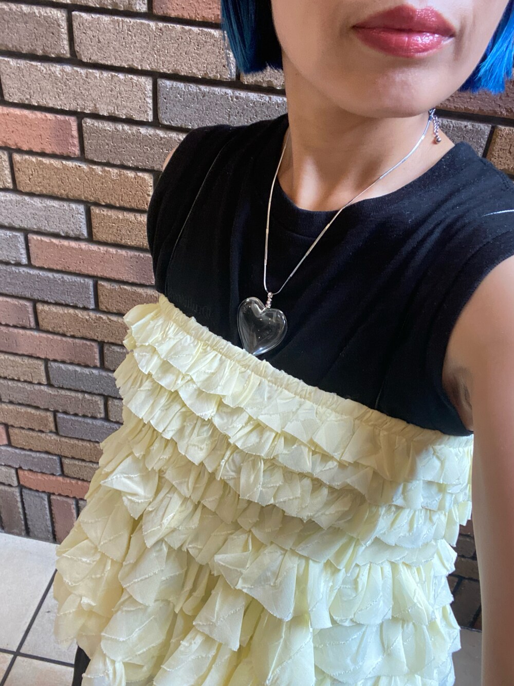 イエロー系のベスト、ブラック系のタンクトップ、ブラック系のその他パンツを着用したレディースの夏コーディネートの2枚目の写真