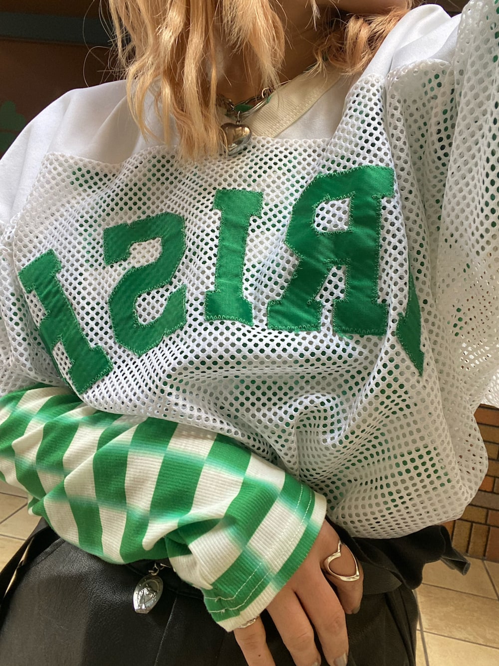 ブラック系のスニーカー、ホワイト系のトップス、グリーン系のトップスを着用したレディースの春コーディネートの3枚目の写真