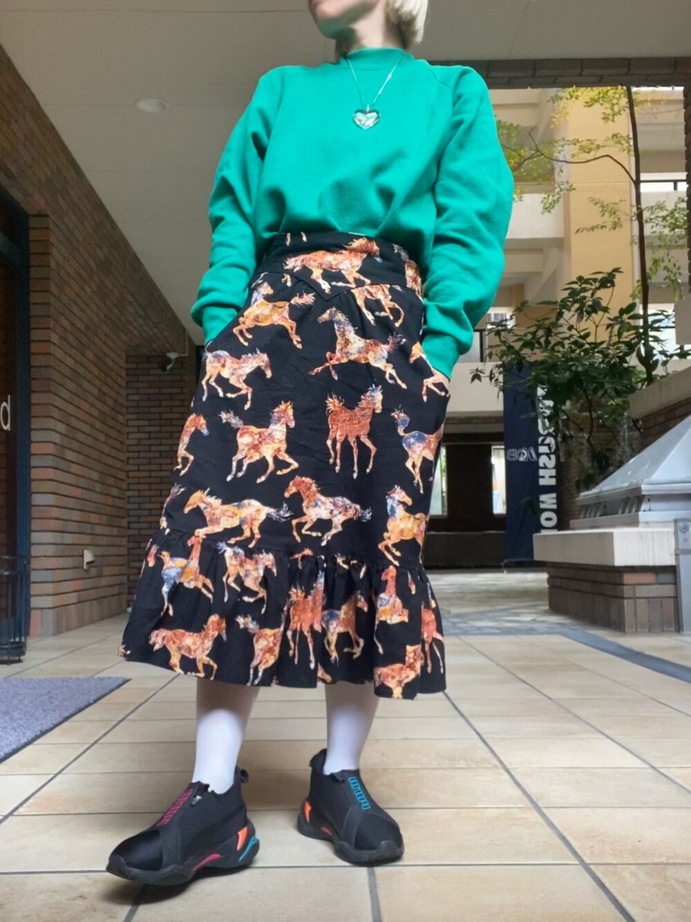 ブラック系のスカート、ブラウン系のカーディガン/ボレロ、グリーン系のスウェットを着用したレディースの冬コーディネートの2枚目の写真