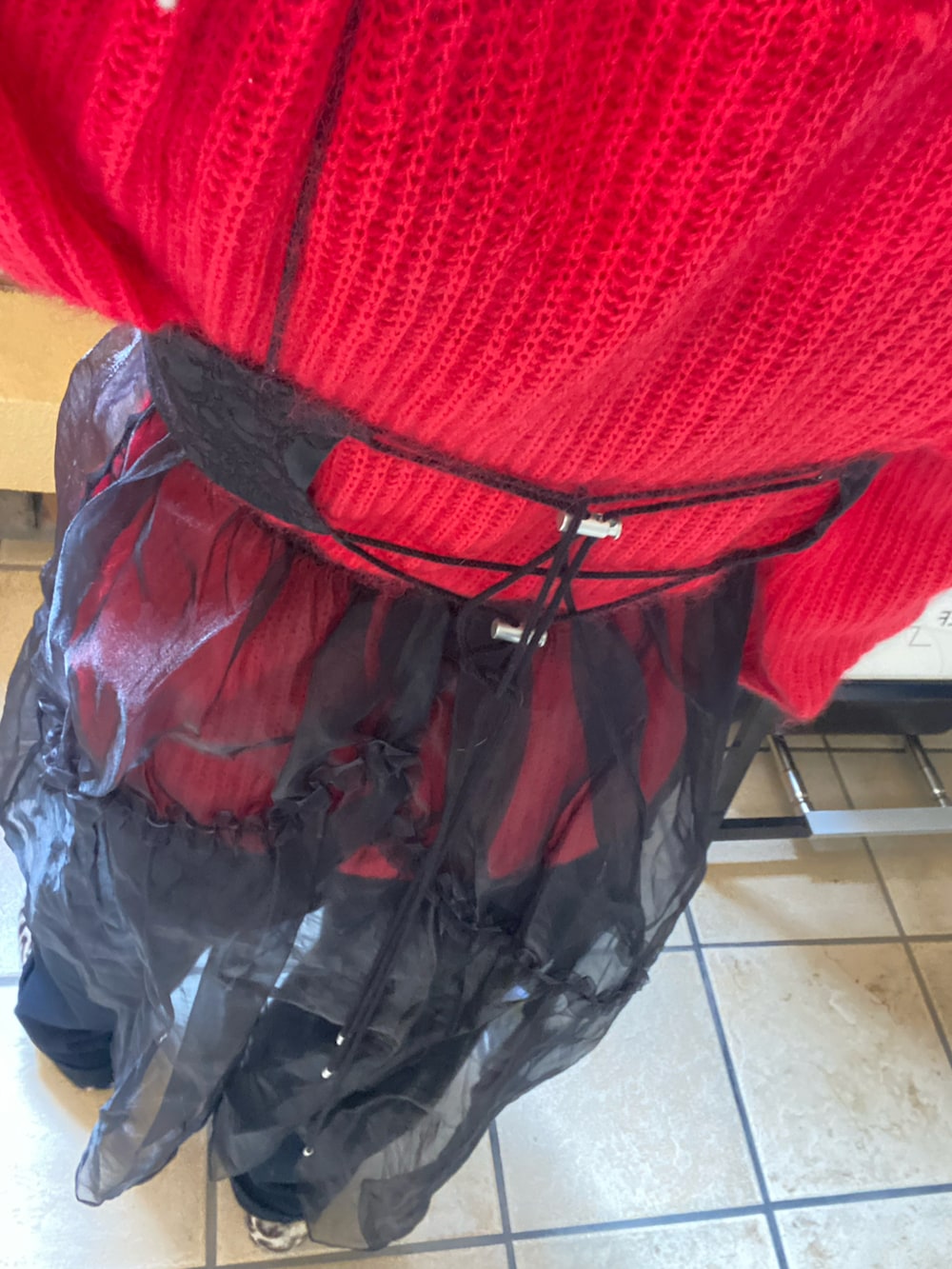 ブラック系のワンピース、レッド系のニット/セーター、ブラック系のスウェットパンツを着用したレディースの冬コーディネートの2枚目の写真