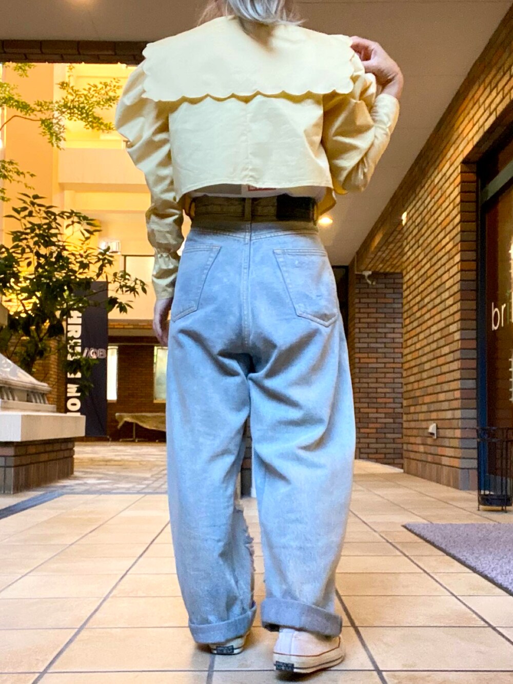 ブルー系のデニムパンツ、イエロー系のシャツ/ブラウス、ホワイト系のTシャツ/カットソーを着用したレディースの秋コーディネートの2枚目の写真