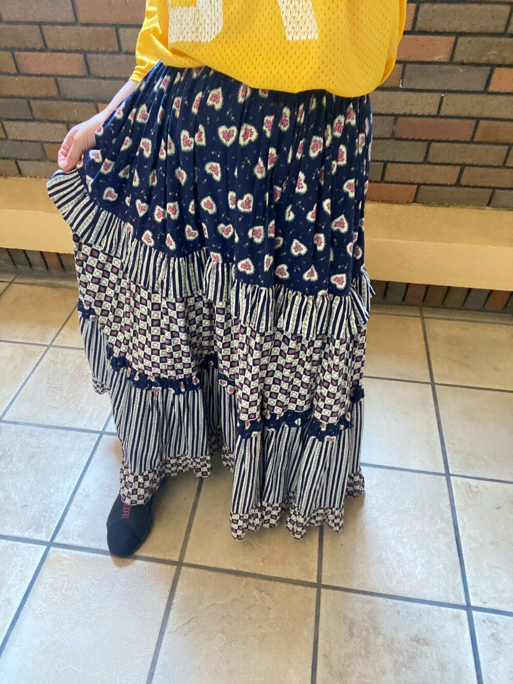 イエロー系のトップス、その他のスカート、ブラック系のスニーカーを着用したレディースの夏コーディネートの3枚目の写真