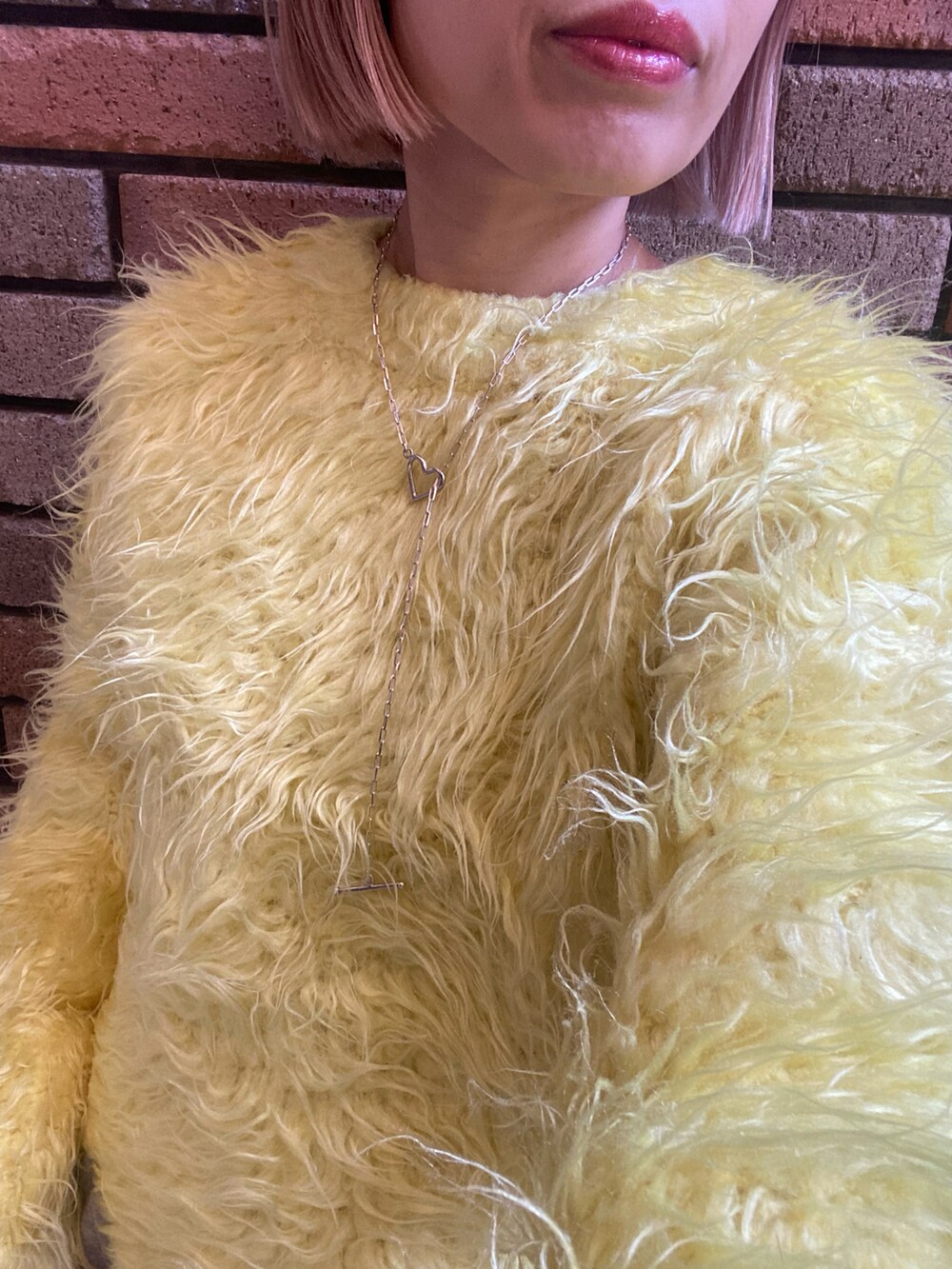イエロー系のニット/セーター、グレー系のスカート、ホワイト系のスウェットパンツを着用したレディースの秋コーディネートの2枚目の写真