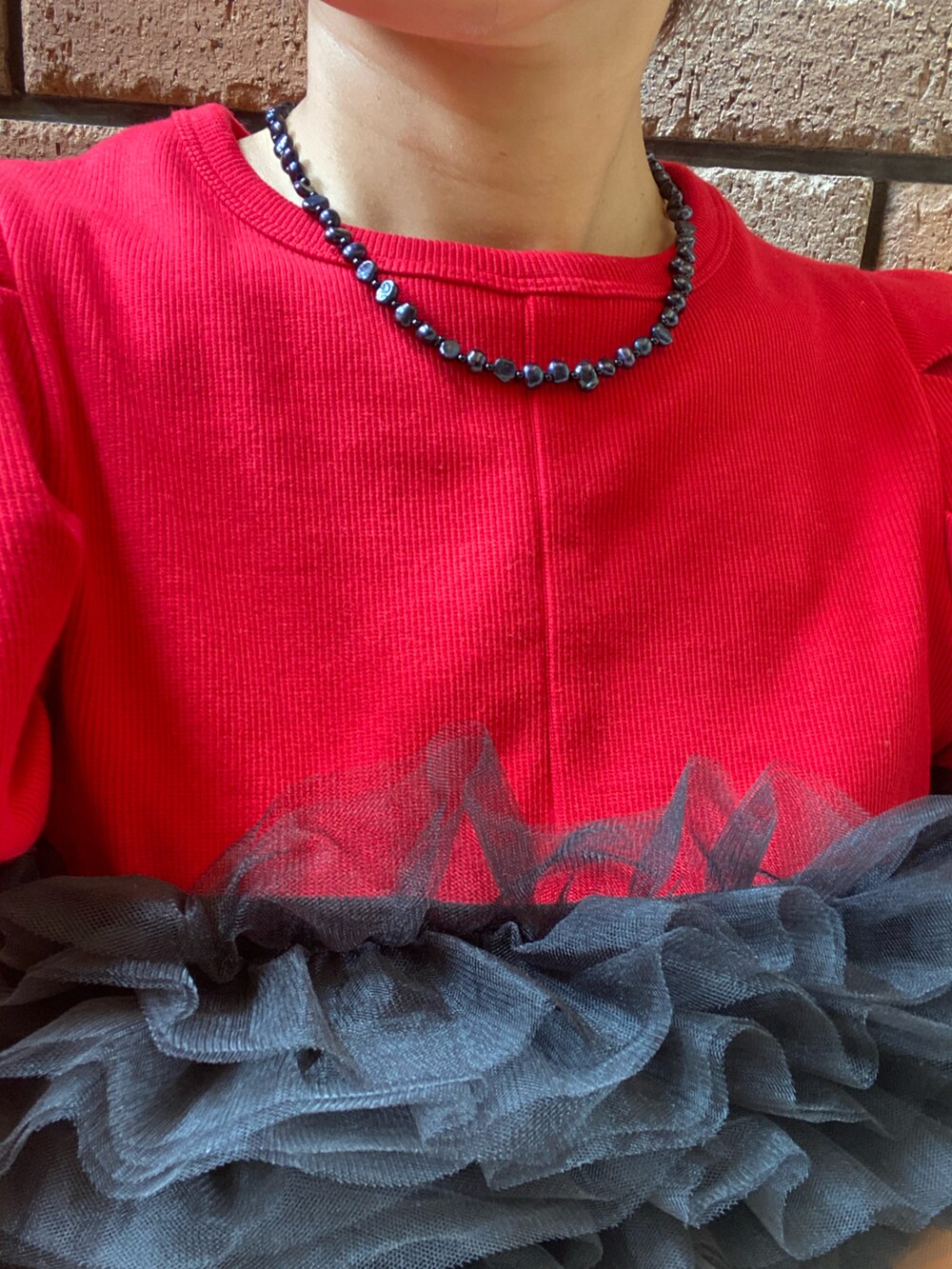 ブラック系のパンツ、ブラック系のその他トップス、レッド系のTシャツ/カットソーを着用したレディースの夏コーディネートの3枚目の写真