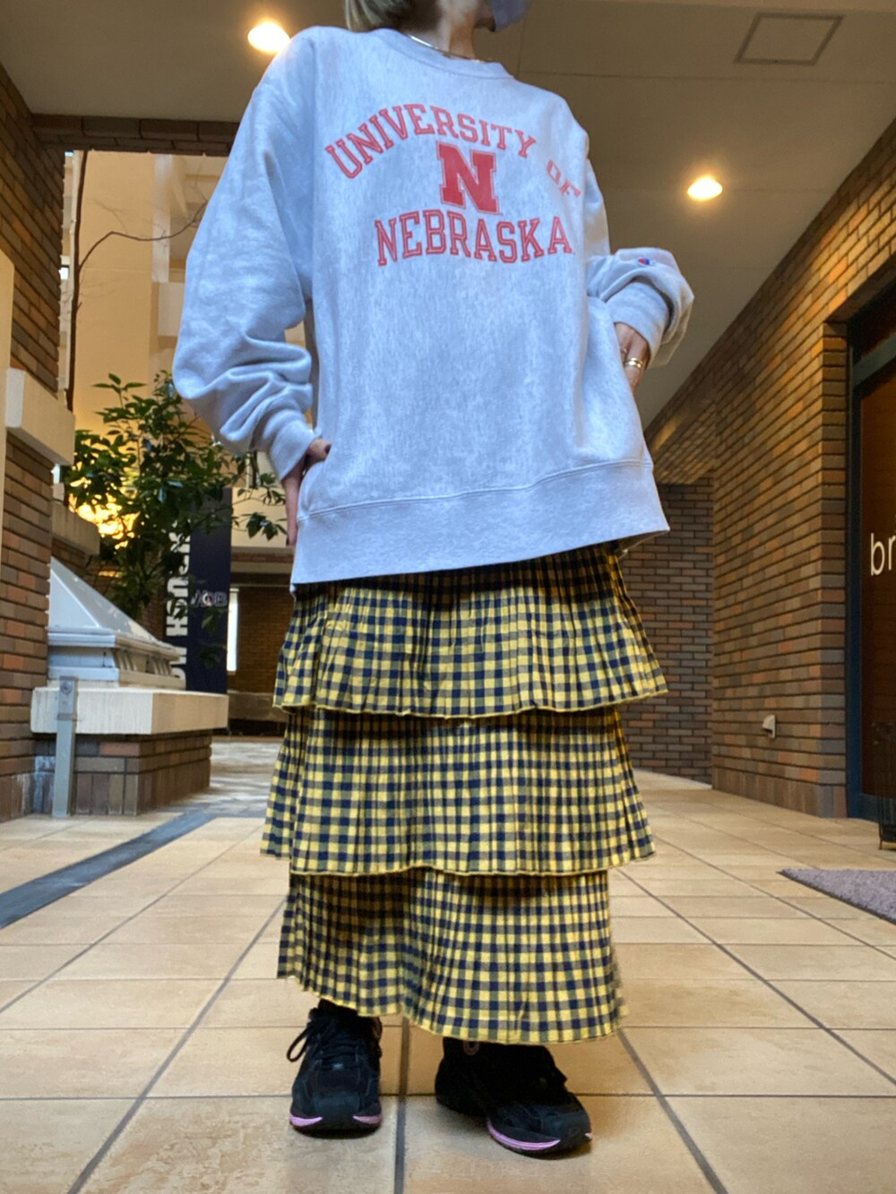 イエロー系のスカート、グリーン系のベスト、ブラック系のスニーカーを着用したレディースの冬コーディネートの2枚目の写真