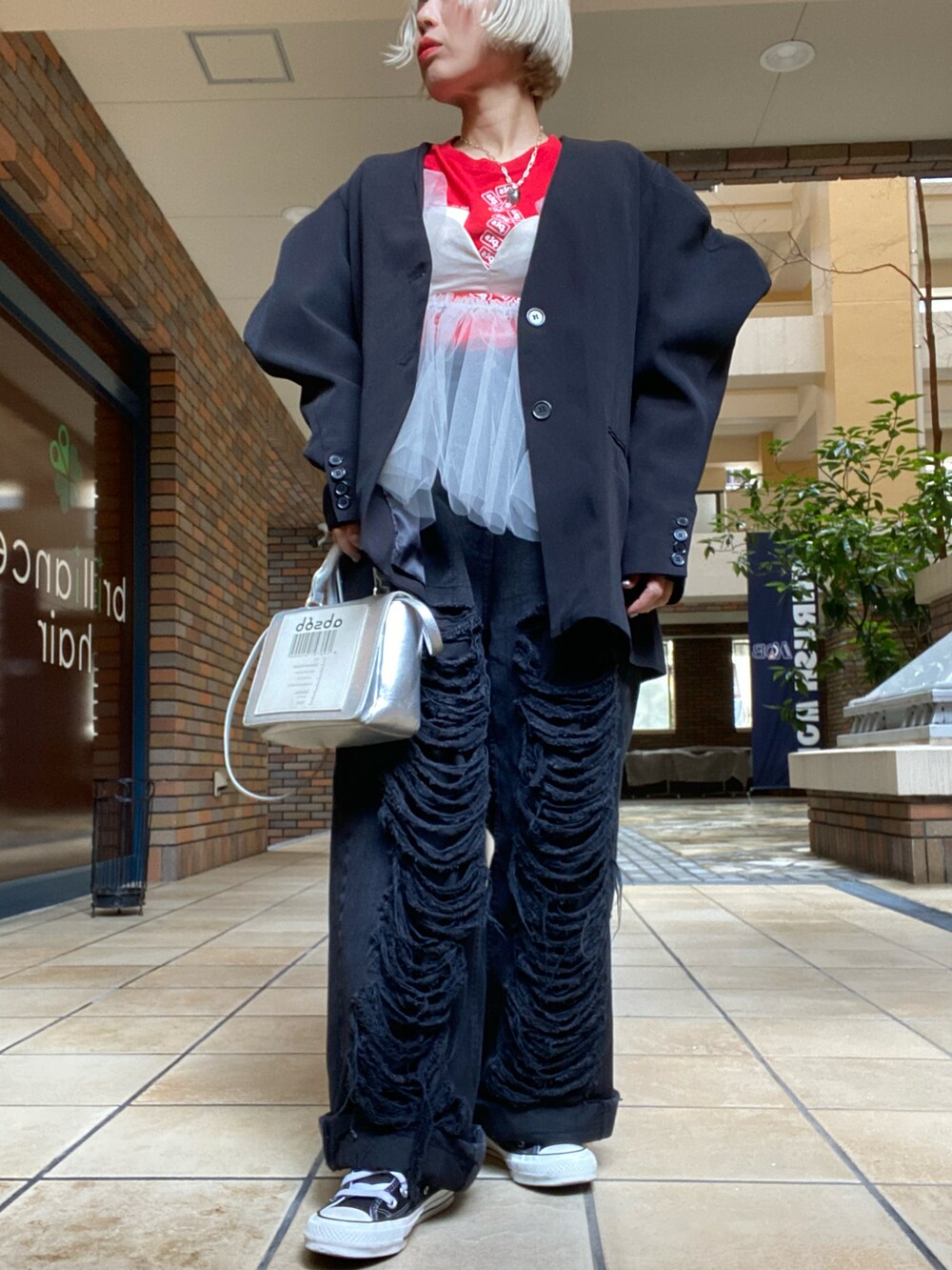 ブラック系のパンツ、ベージュ系のベスト、レッド系のTシャツ/カットソーを着用したレディースの春コーディネートの3枚目の写真