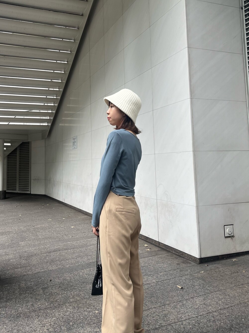 ブルー系のTシャツ/カットソー、ベージュ系のスラックス、ブラック系のバッグを着用したレディースの秋コーディネートの2枚目の写真