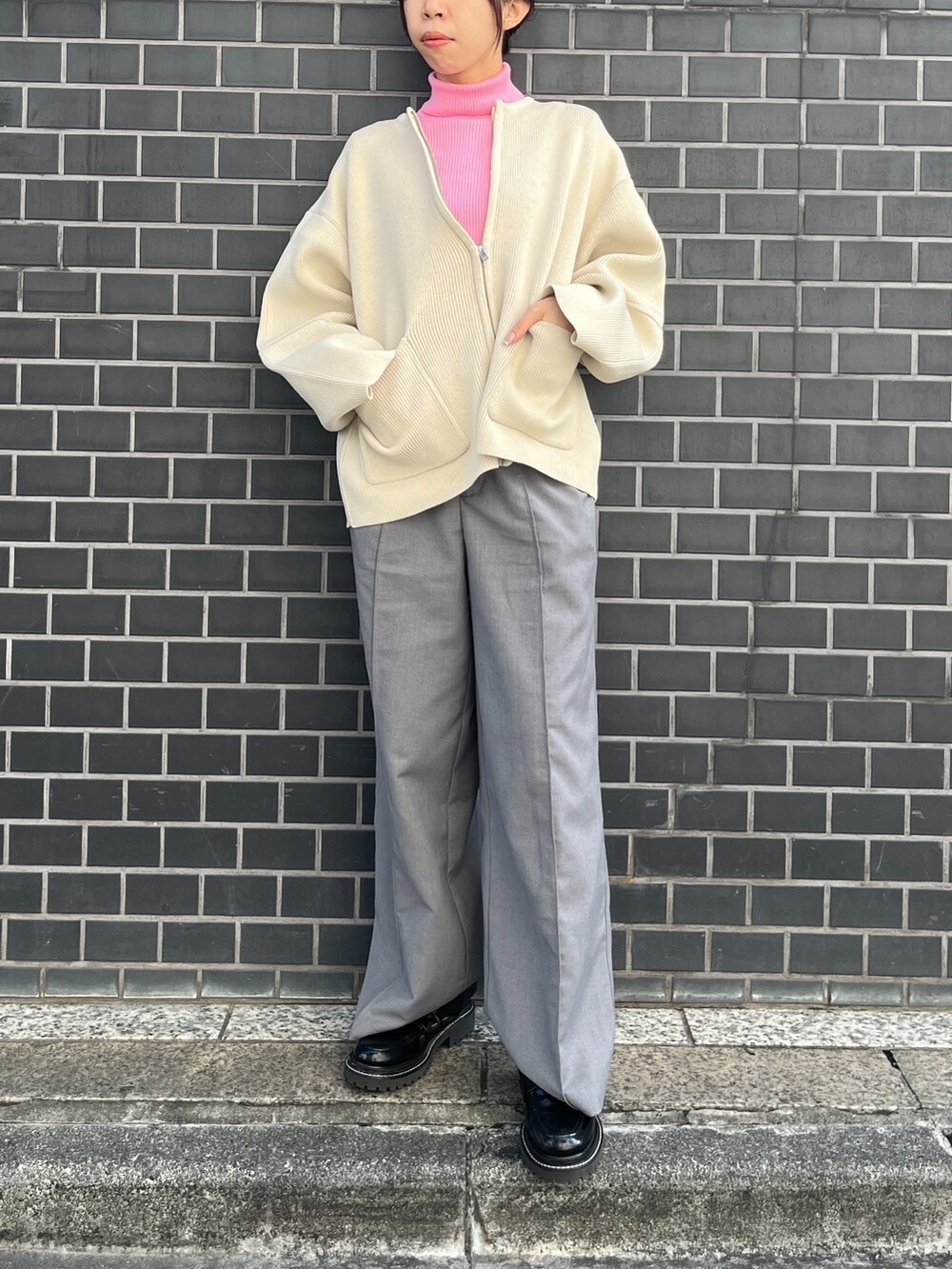 ホワイト系のカーディガン/ボレロ、グレー系のスラックス、ピンク系のニット/セーターを着用したレディースの秋コーディネートの2枚目の写真