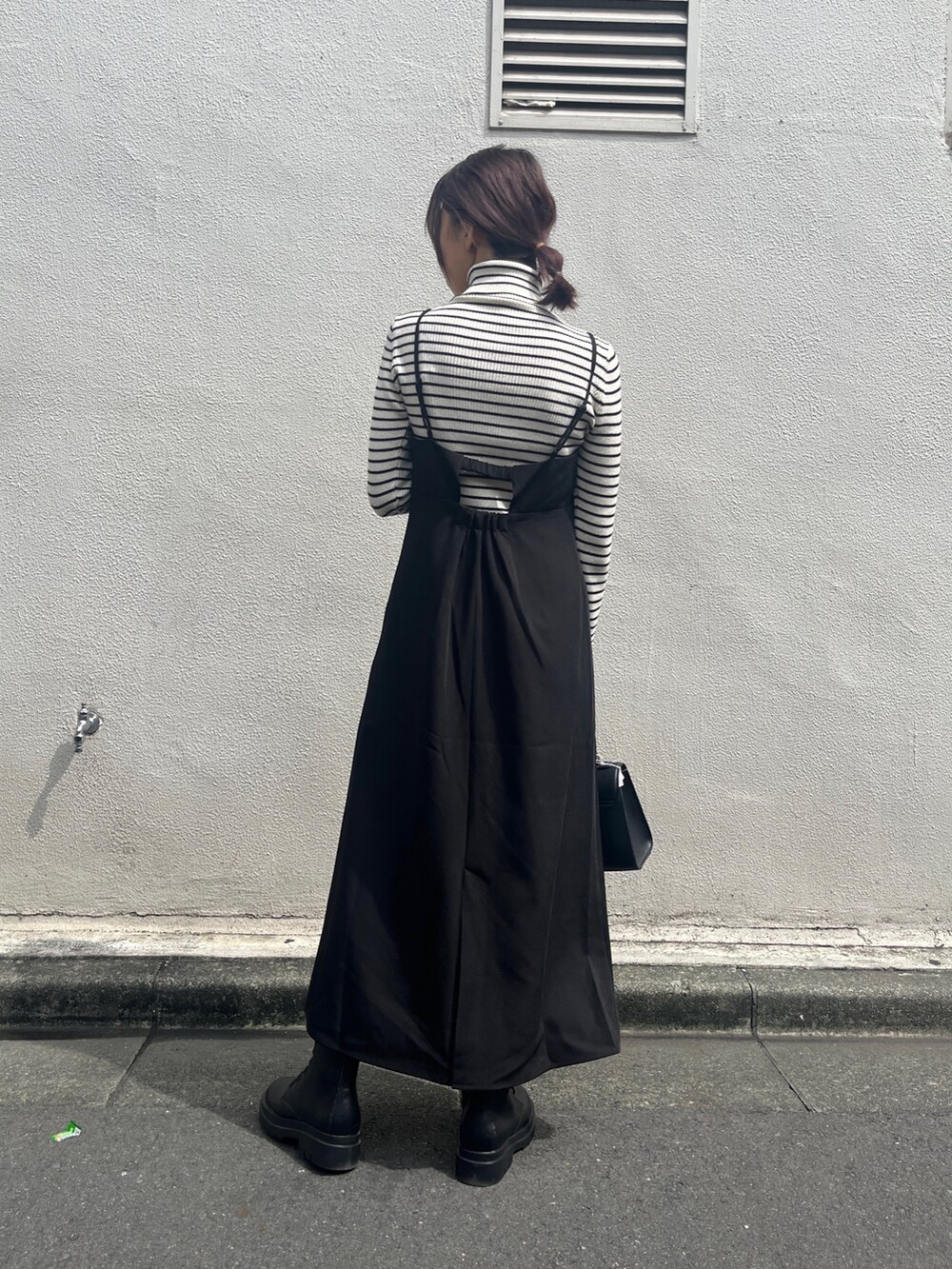 ブラック系のワンピース、ホワイト系のニット/セーター、ブラック系のブーツを着用したレディースの秋コーディネートの2枚目の写真