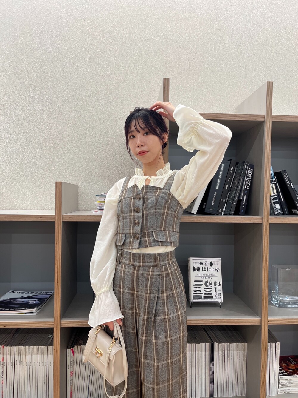 グレー系のスラックス、ブラック系のパンプス、ホワイト系のショルダーバッグを着用したレディースの秋コーディネートの2枚目の写真