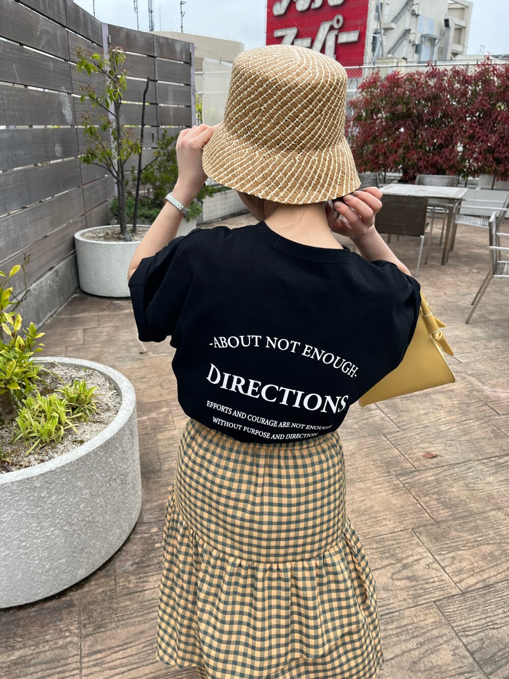 イエロー系のスカート、ブラック系のTシャツ/カットソー、イエロー系のショルダーバッグを着用したレディースの夏コーディネートの3枚目の写真