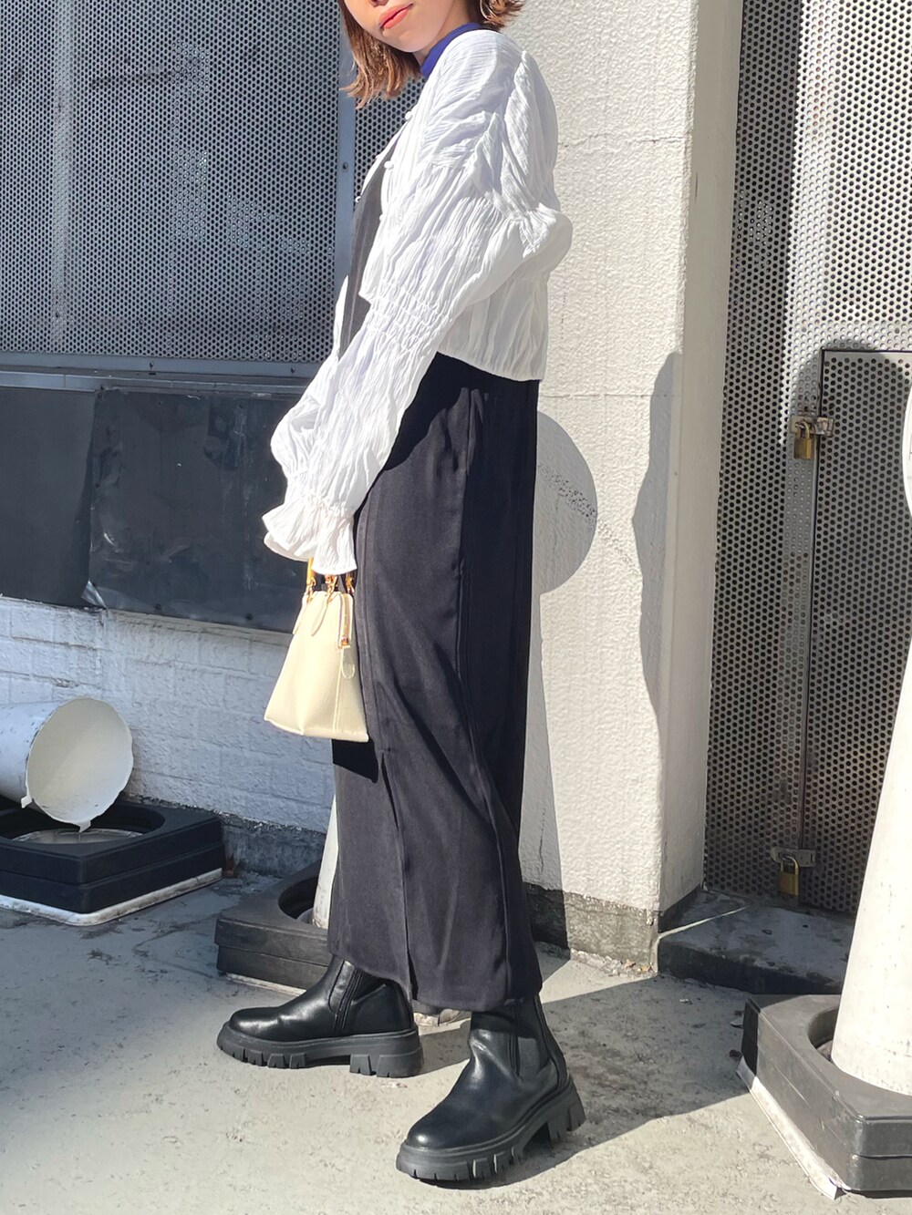 ブラック系のワンピース、ホワイト系のショルダーバッグ、ホワイト系のシャツ/ブラウスを着用したレディースの冬コーディネートの2枚目の写真