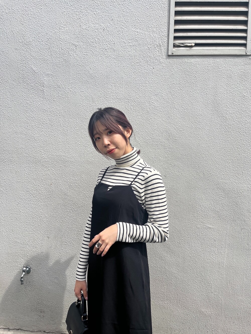 ブラック系のワンピース、ホワイト系のニット/セーター、ブラック系のブーツを着用したレディースの秋コーディネートの5枚目の写真