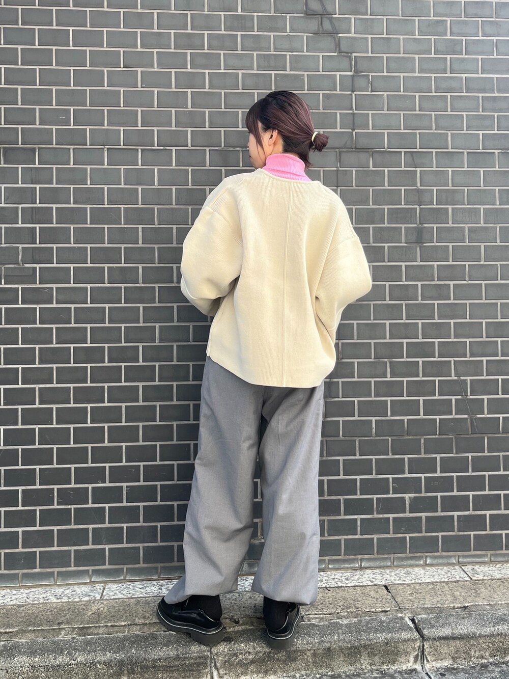 ホワイト系のカーディガン/ボレロ、グレー系のスラックス、ピンク系のニット/セーターを着用したレディースの秋コーディネートの3枚目の写真