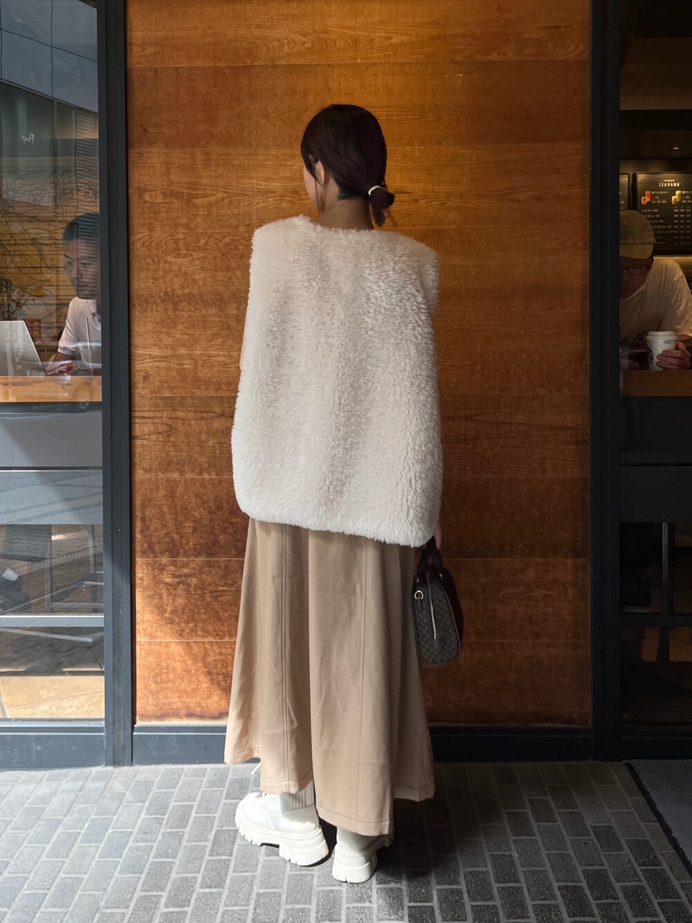 ブラウン系のボストンバッグ、ベージュ系のワンピース、ホワイト系のベストを着用したレディースの秋コーディネートの3枚目の写真