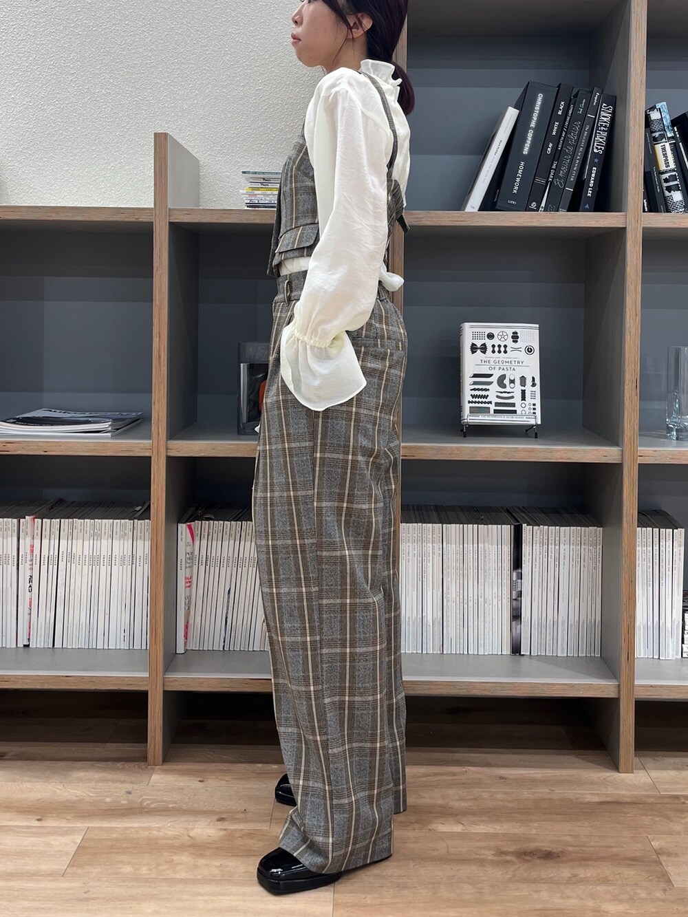 グレー系のスラックス、ブラック系のパンプス、ホワイト系のショルダーバッグを着用したレディースの秋コーディネートの3枚目の写真