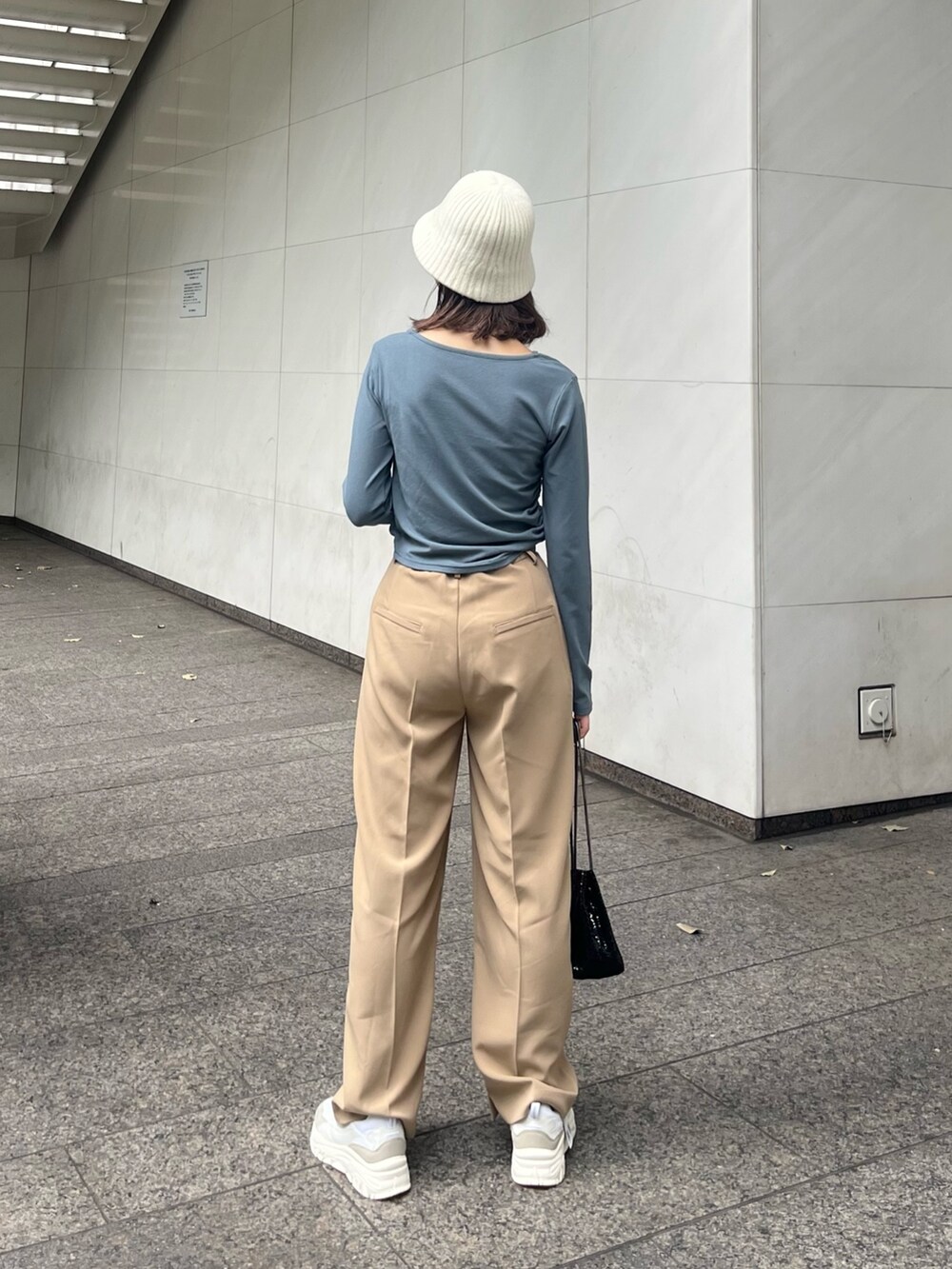 ブルー系のTシャツ/カットソー、ベージュ系のスラックス、ブラック系のバッグを着用したレディースの秋コーディネートの4枚目の写真
