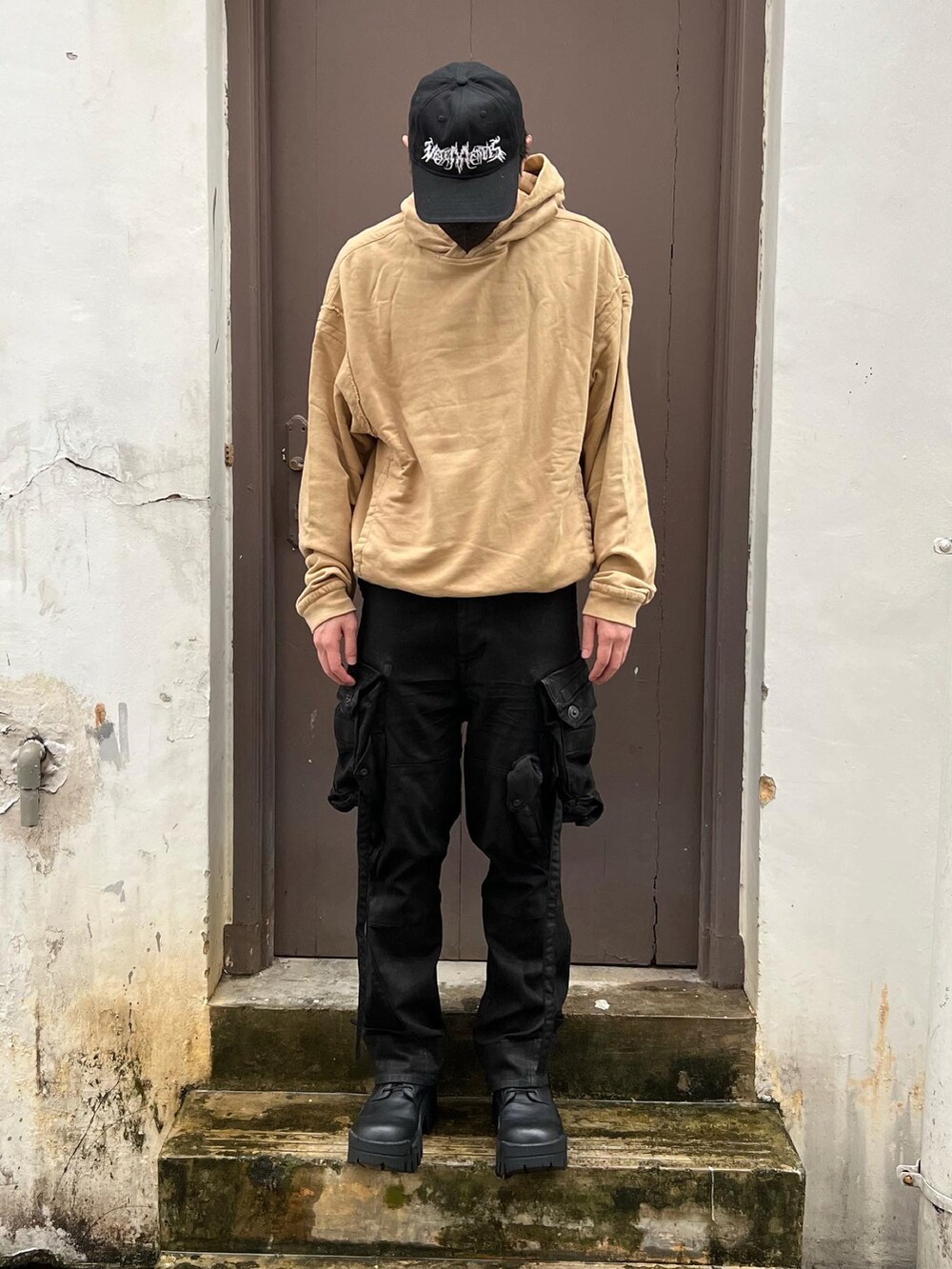 ゴールド系のパーカー、ブラック系のカーゴパンツ、ブラック系のブーツを着用したメンズの春コーディネートの2枚目の写真