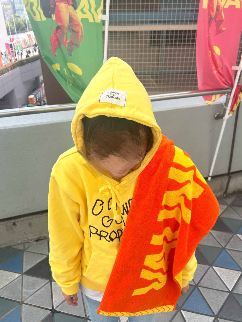 イエロー系のパーカー、グレー系のデニムパンツを着用したレディースの冬コーディネートの2枚目の写真