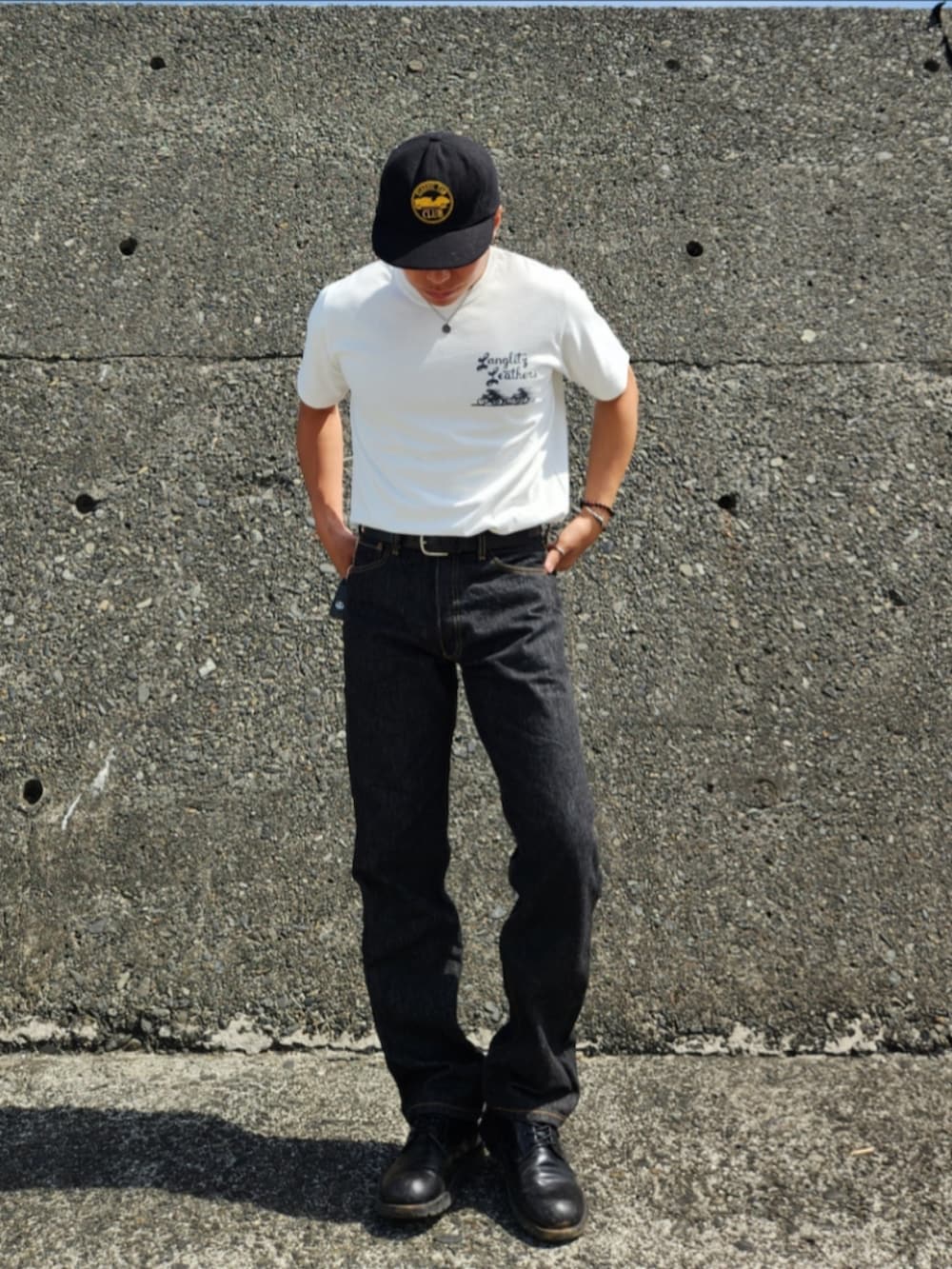ブラック系のデニムパンツ、ブラック系のブーツ、ホワイト系のTシャツ/カットソーを着用したメンズの春コーディネートの3枚目の写真