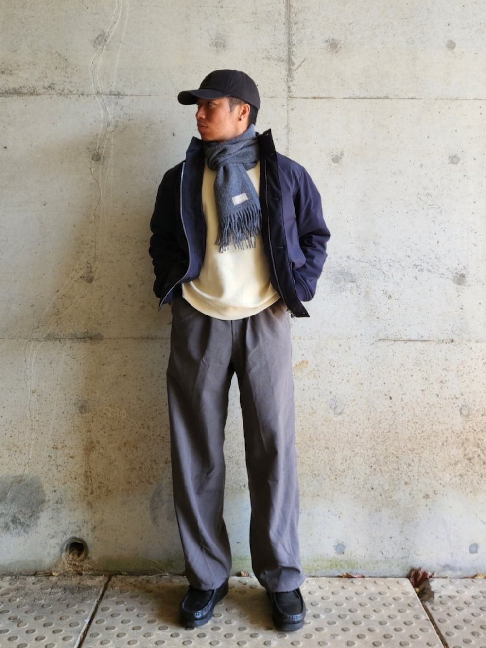 グレー系のスラックス、ブラック系のローファー、ホワイト系のスウェットを着用したメンズの秋コーディネートの2枚目の写真