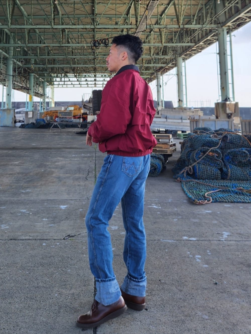 レッド系のナイロンジャケット、ブルー系のデニムパンツ、ブラウン系のブーツを着用したメンズの冬コーディネートの3枚目の写真