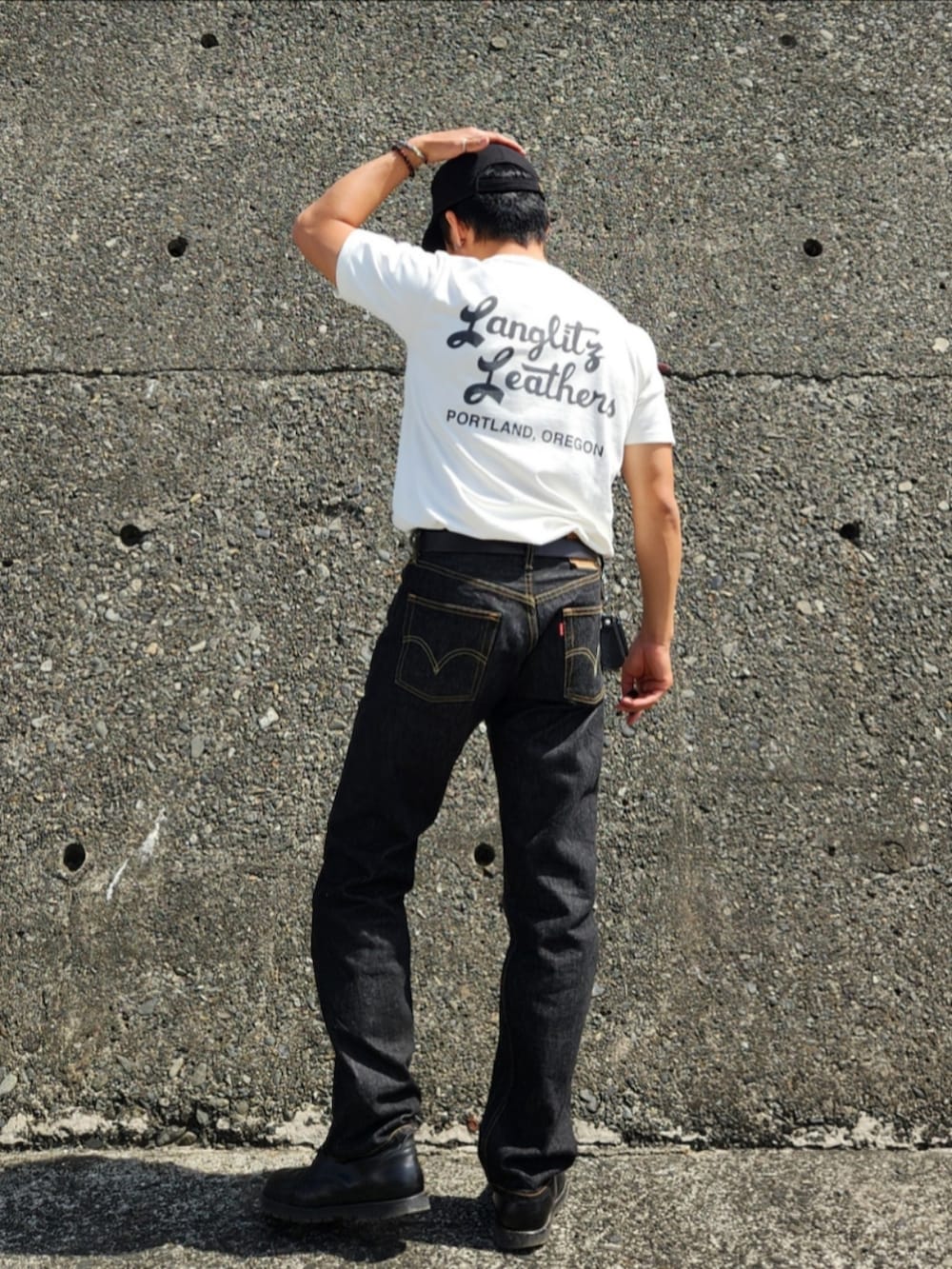 ブラック系のデニムパンツ、ブラック系のブーツ、ホワイト系のTシャツ/カットソーを着用したメンズの春コーディネートの4枚目の写真