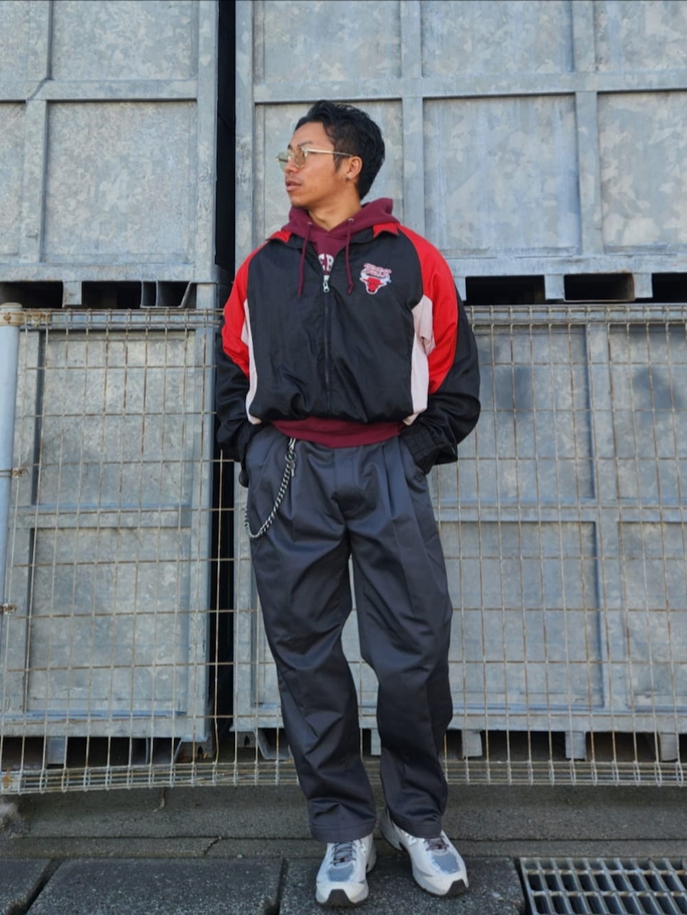 ブラック系のナイロンジャケット、レッド系のパーカー、グレー系のチノパンツを着用したメンズの秋コーディネートの3枚目の写真
