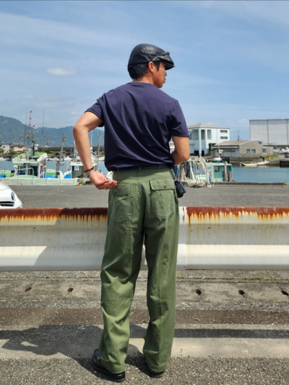 グリーン系のカーゴパンツ、ブラック系のローファー、ブラック系のTシャツ/カットソーを着用したメンズの春コーディネートの4枚目の写真