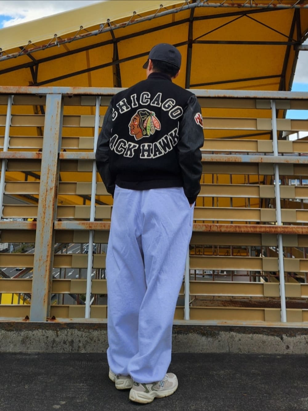 グレー系のスウェットパンツ、ホワイト系のスニーカー、ブラック系のスタジャンを着用したメンズの冬コーディネートの3枚目の写真