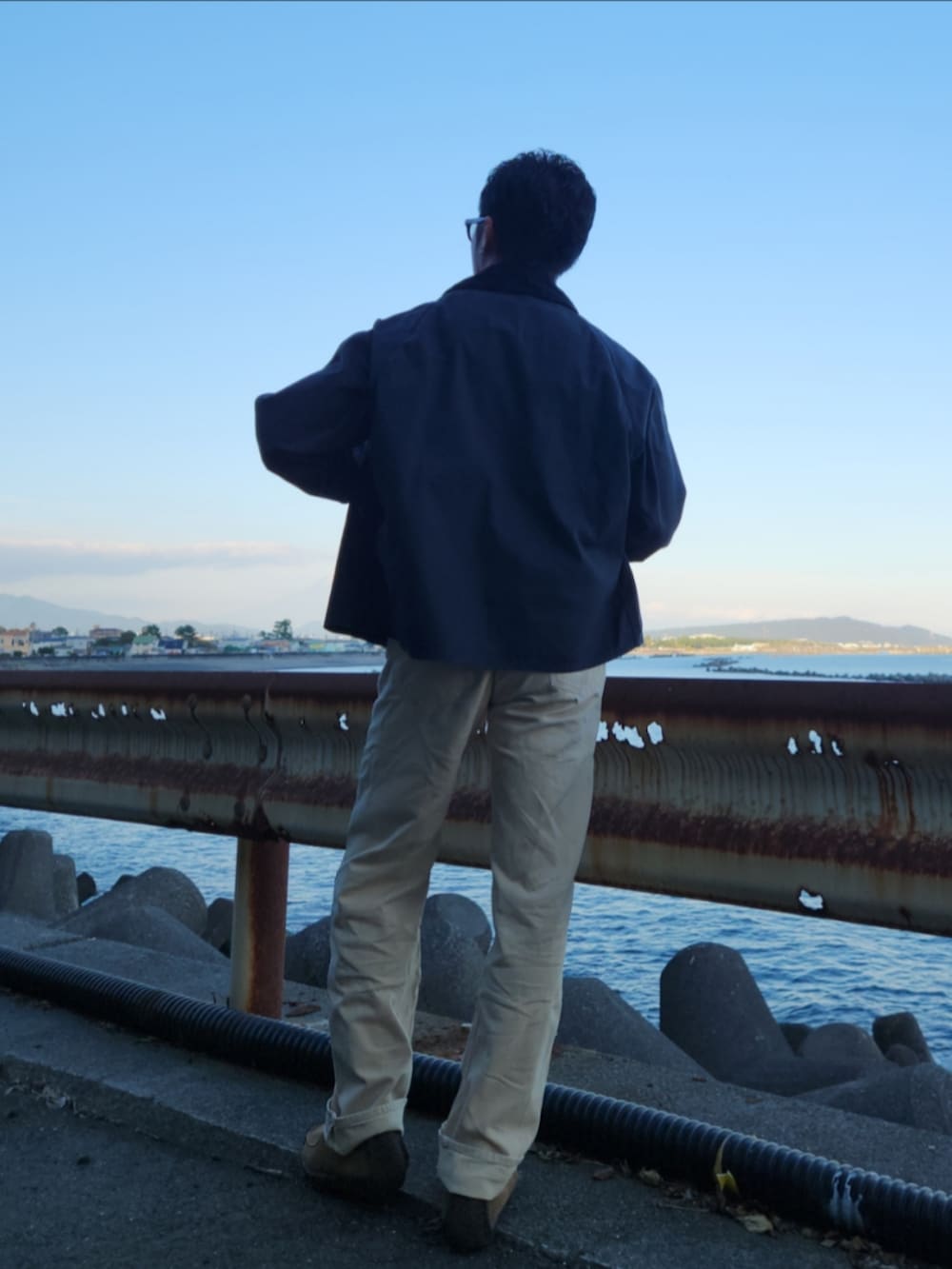 ブラック系のジャケット/アウター、イエロー系のトップス、ホワイト系のデニムパンツを着用したメンズの秋コーディネートの3枚目の写真