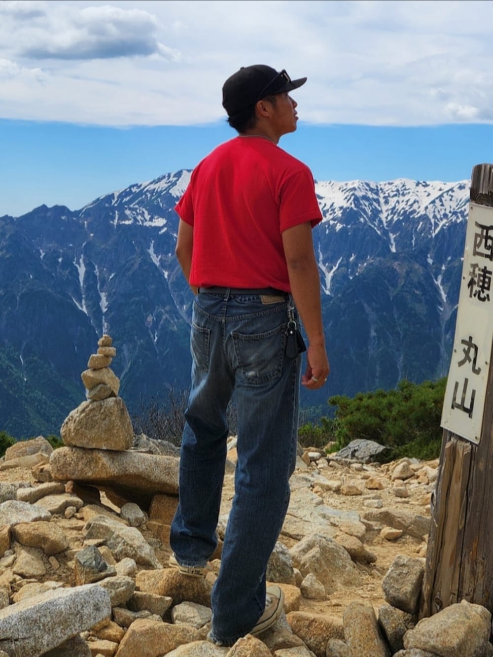 レッド系のTシャツ/カットソー、ブルー系のデニムパンツ、ベージュ系のスニーカーを着用したメンズの春コーディネートの4枚目の写真