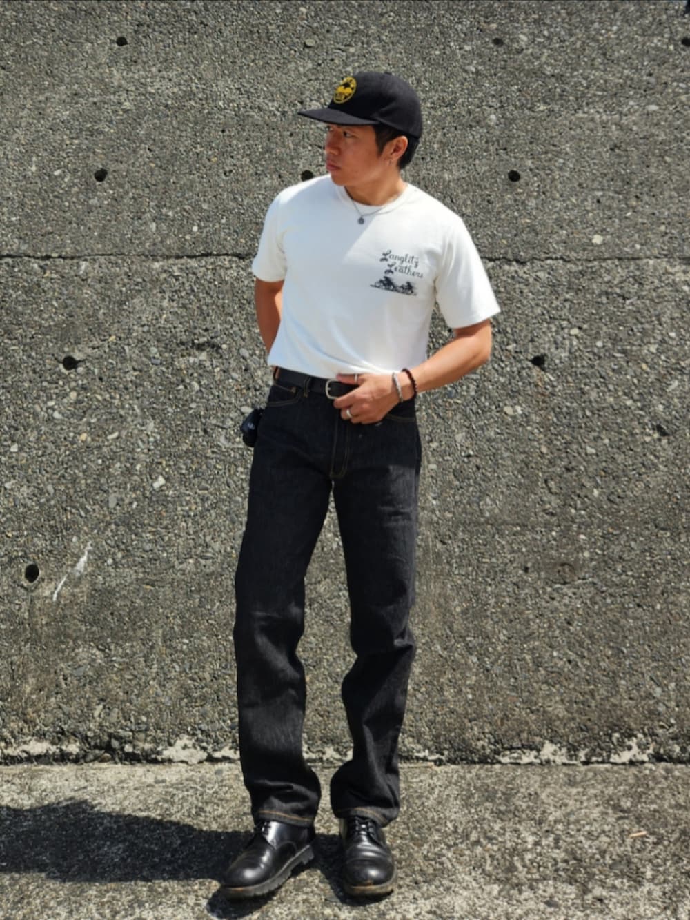 ブラック系のデニムパンツ、ブラック系のブーツ、ホワイト系のTシャツ/カットソーを着用したメンズの春コーディネートの2枚目の写真