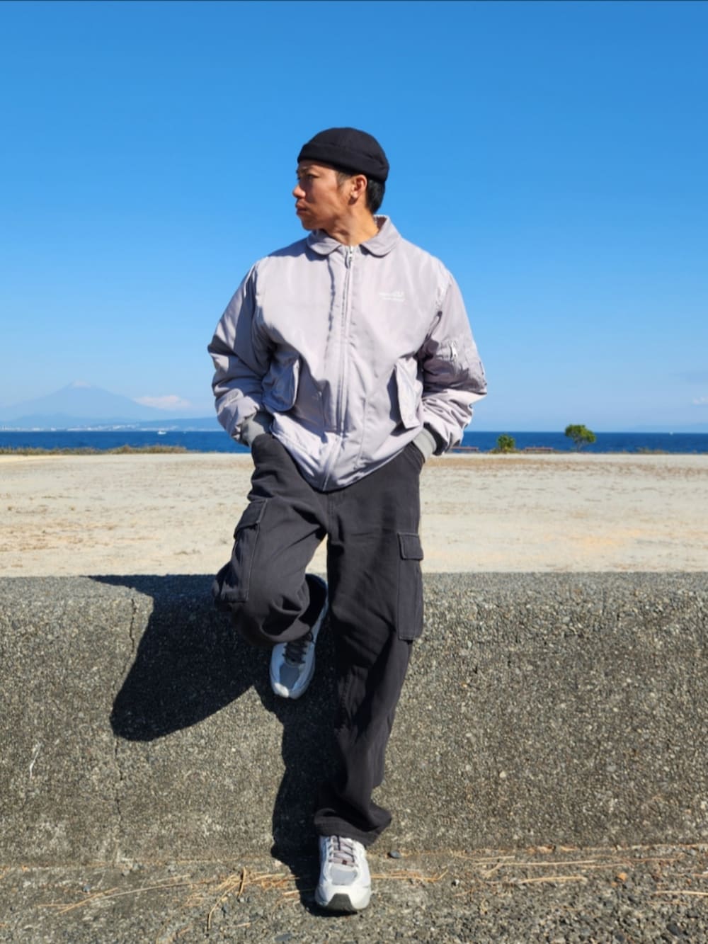 グレー系のミリタリージャケット、ブラック系のカーゴパンツ、グレー系のスニーカーを着用したメンズの秋コーディネートの2枚目の写真