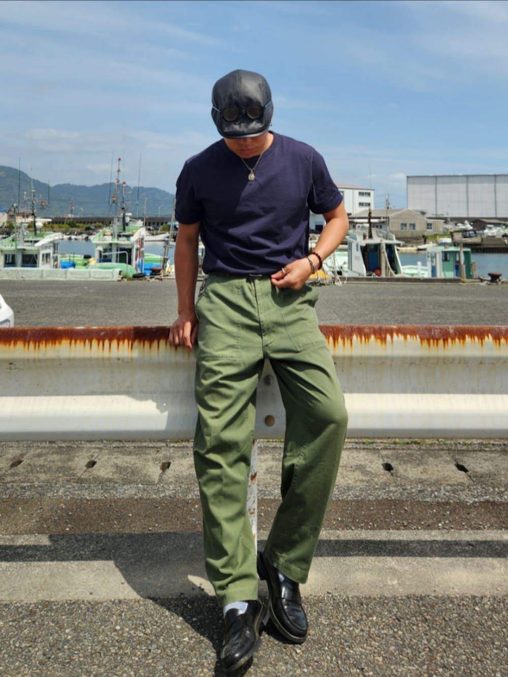 グリーン系のカーゴパンツ、ブラック系のローファー、ブラック系のTシャツ/カットソーを着用したメンズの春コーディネートの3枚目の写真