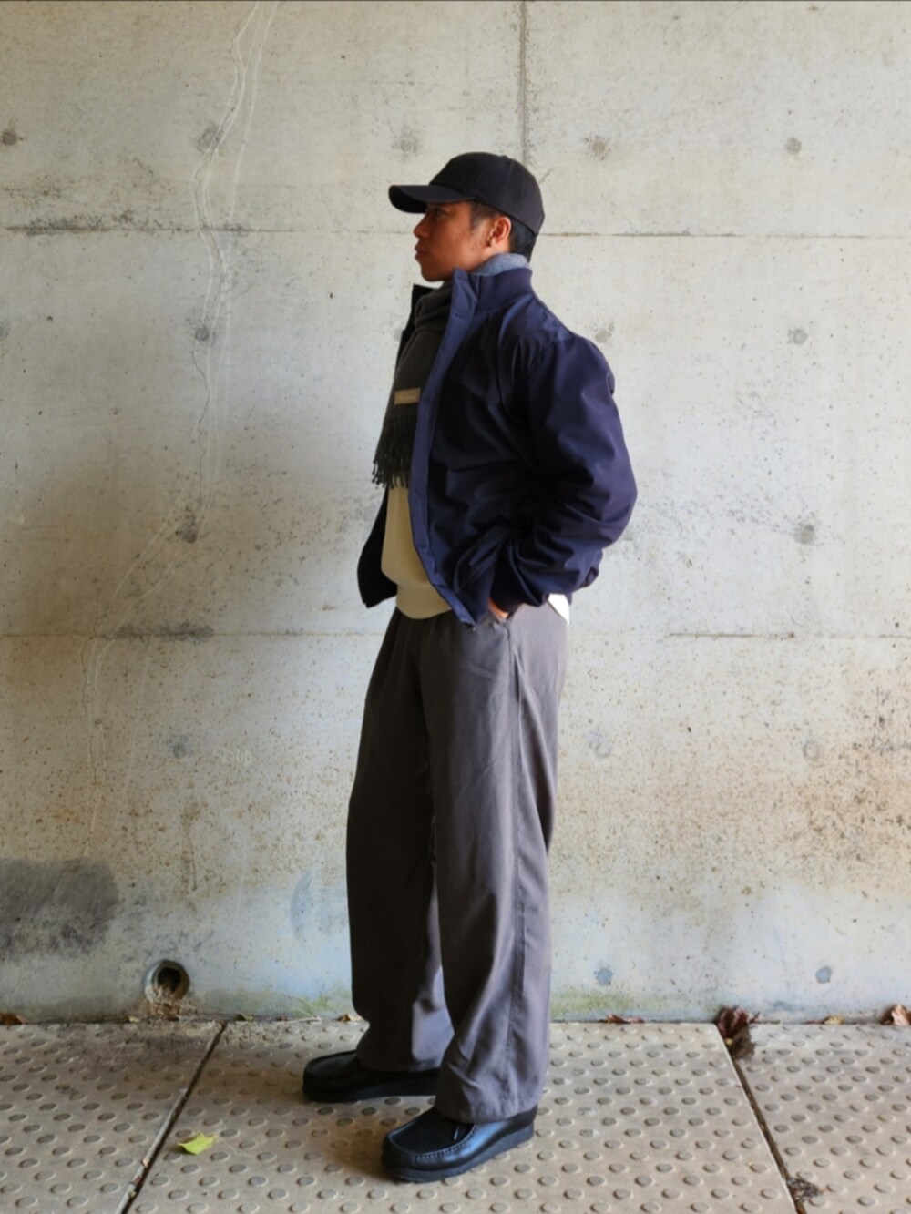 グレー系のスラックス、ブラック系のローファー、ホワイト系のスウェットを着用したメンズの秋コーディネートの3枚目の写真