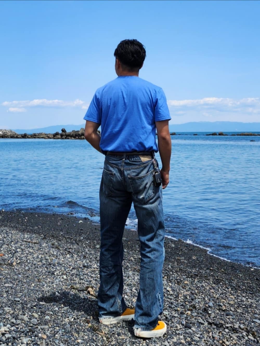 ブルー系のTシャツ/カットソー、ブルー系のデニムパンツ、イエロー系のスニーカーを着用したメンズの春コーディネートの3枚目の写真