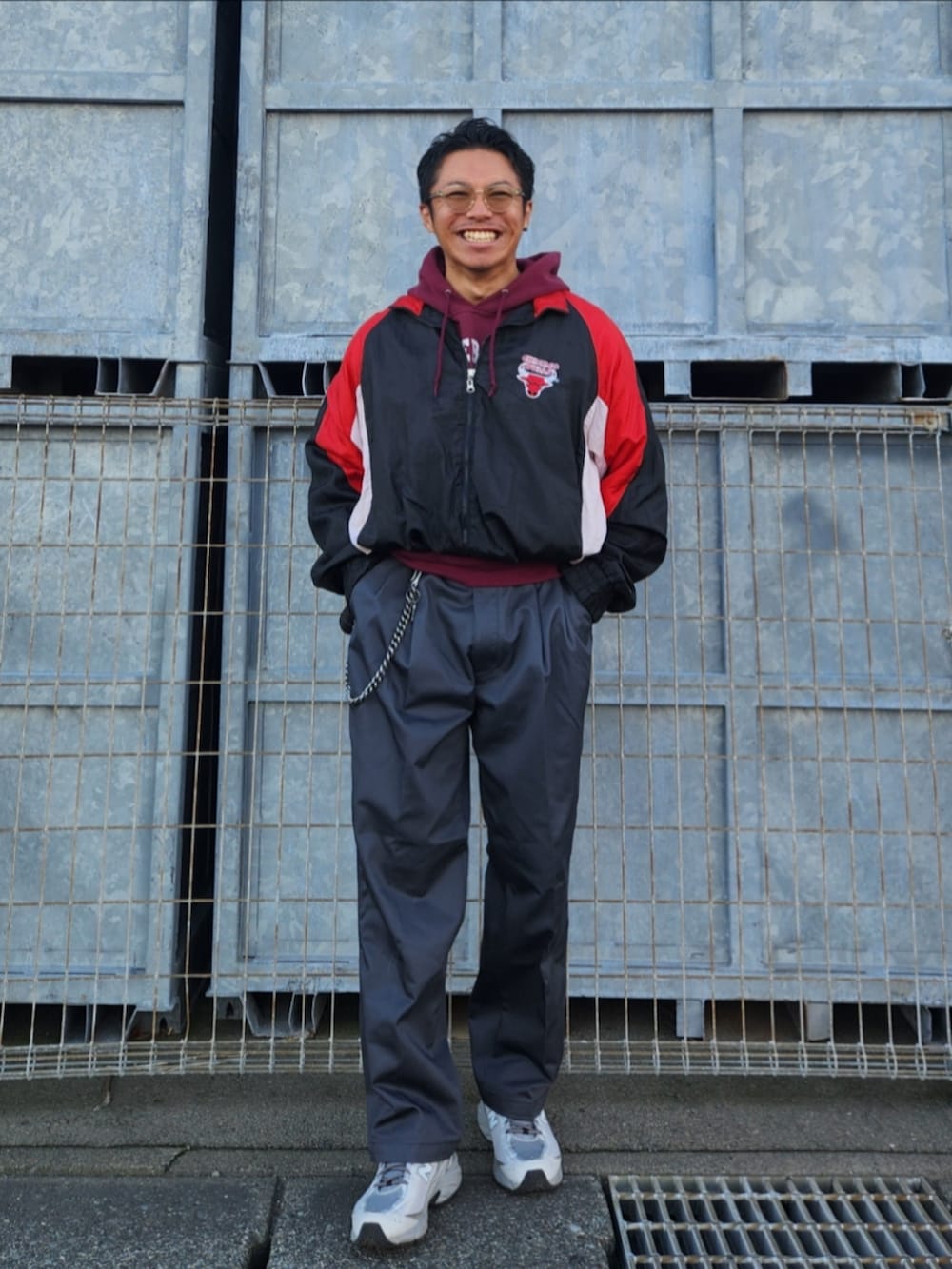 ブラック系のナイロンジャケット、レッド系のパーカー、グレー系のチノパンツを着用したメンズの秋コーディネートの2枚目の写真