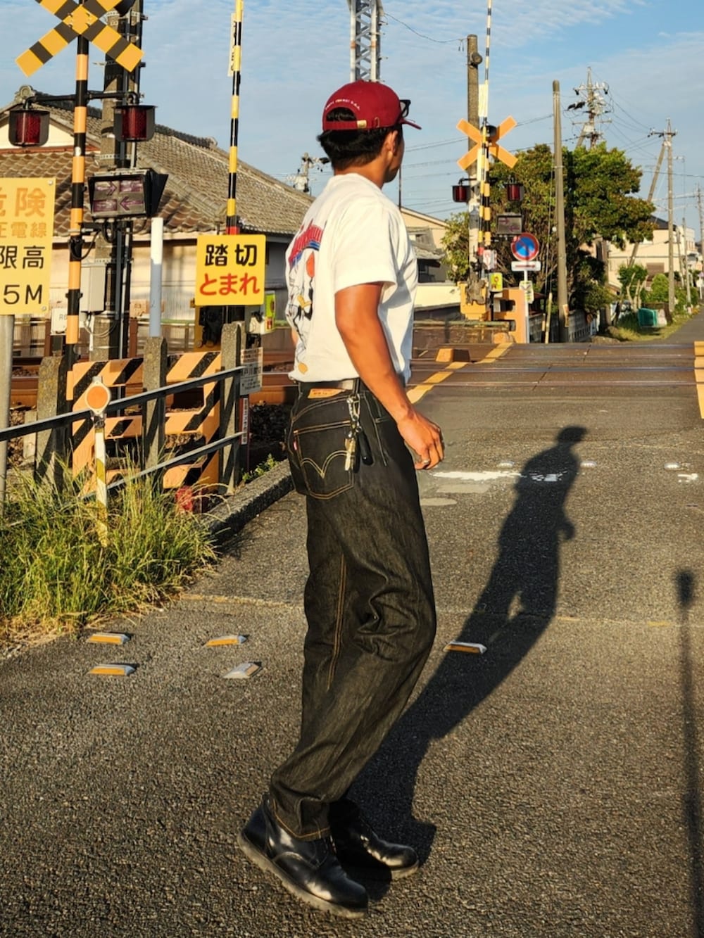 ホワイト系のTシャツ/カットソー、ブラック系のデニムパンツ、ブラック系のブーツを着用したメンズの春コーディネートの3枚目の写真