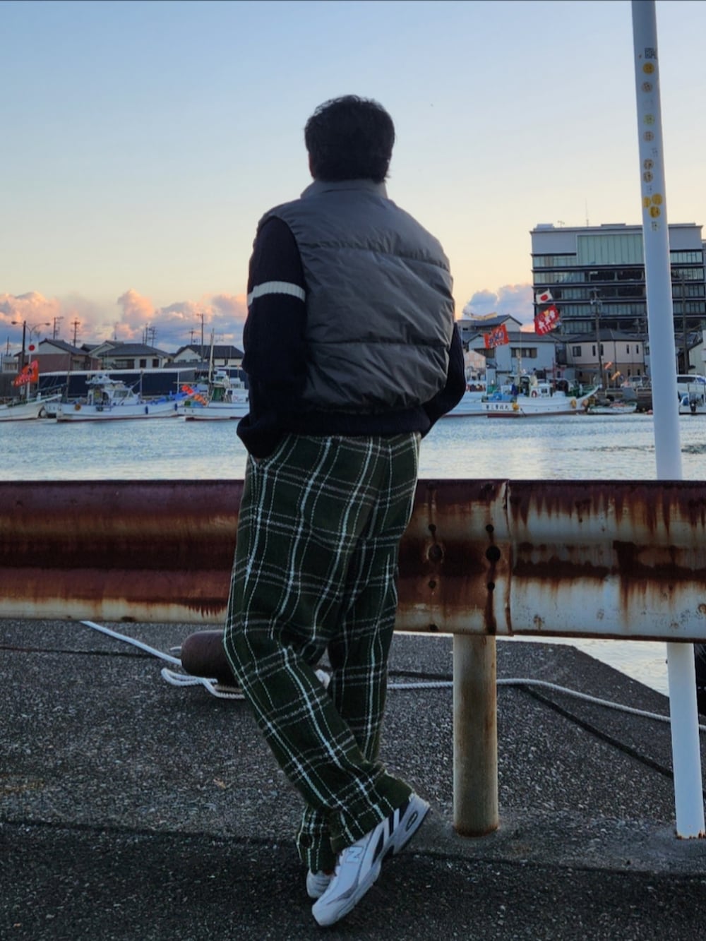 グレー系のダウンベスト、ブラック系のニット/セーター、グリーン系のパンツを着用したメンズの冬コーディネートの3枚目の写真